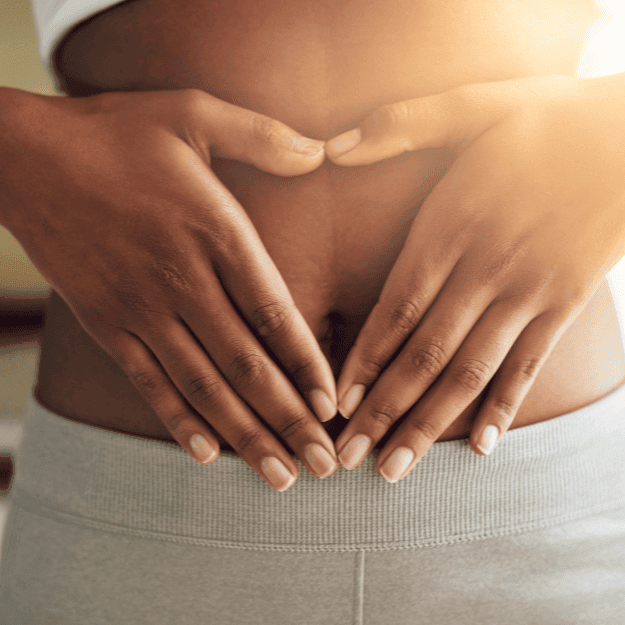 A women's torso with her hands resting on her stomach in a heart shape depicting Will a Plant-Based Diet Really Improve Gut Health