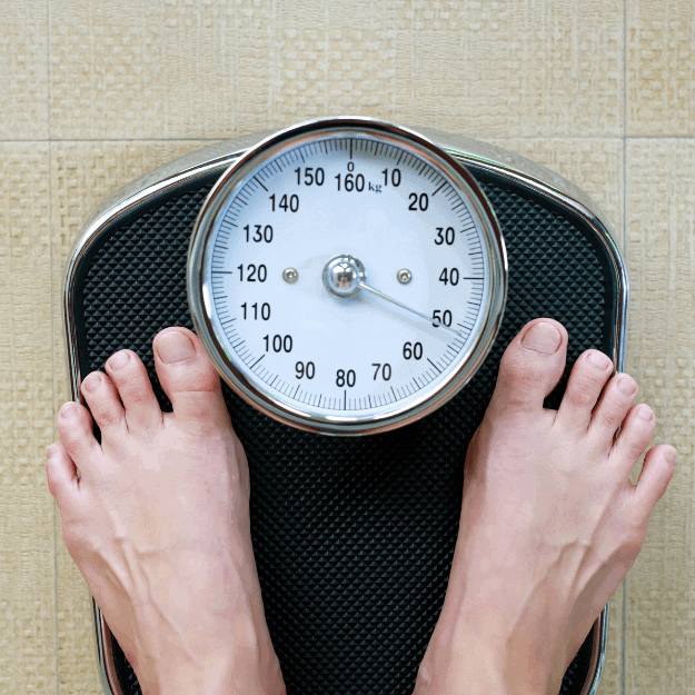 A mans feet on weighing scales depicting Does Eating Less Meat Help with Weight Loss?