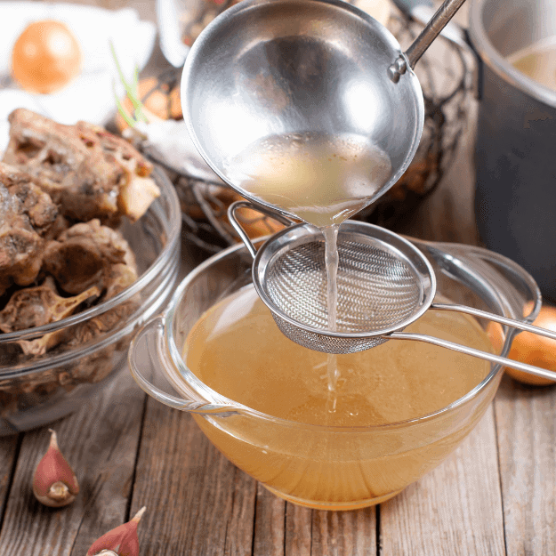 Bone broth being sieved denoting the process of making bone broth