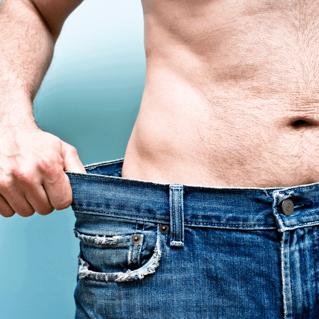 A slim man showing the gap around his trousers depicting weight loss from eating eggs